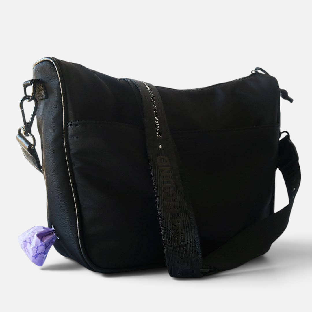 The Dog Emporium Day Tripper bag in black canvas with an adjustable logo strap and integrated poop bag dispenser.