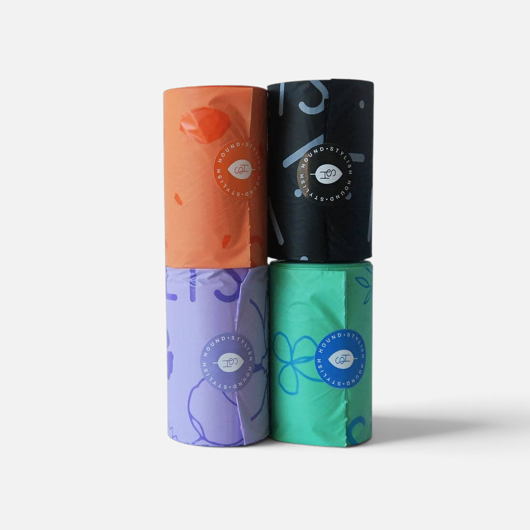 The Dog Emporium biodegradable poop bag rolls in lilac, orange, black, and aqua with patterned corn starch material.