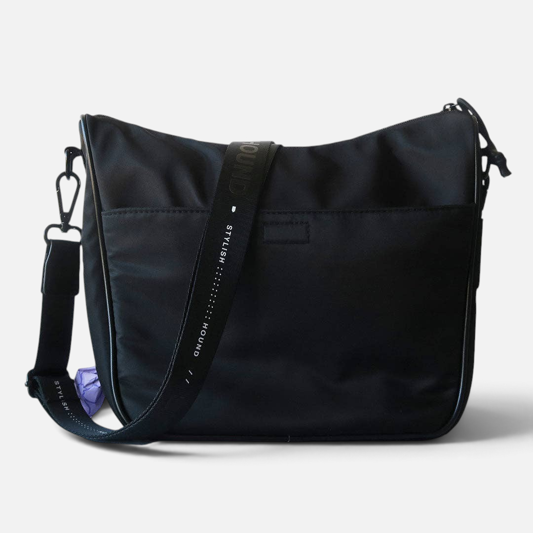 The Dog Emporium Day Tripper bag in black canvas with an adjustable logo shoulder strap and side poop bag dispenser.