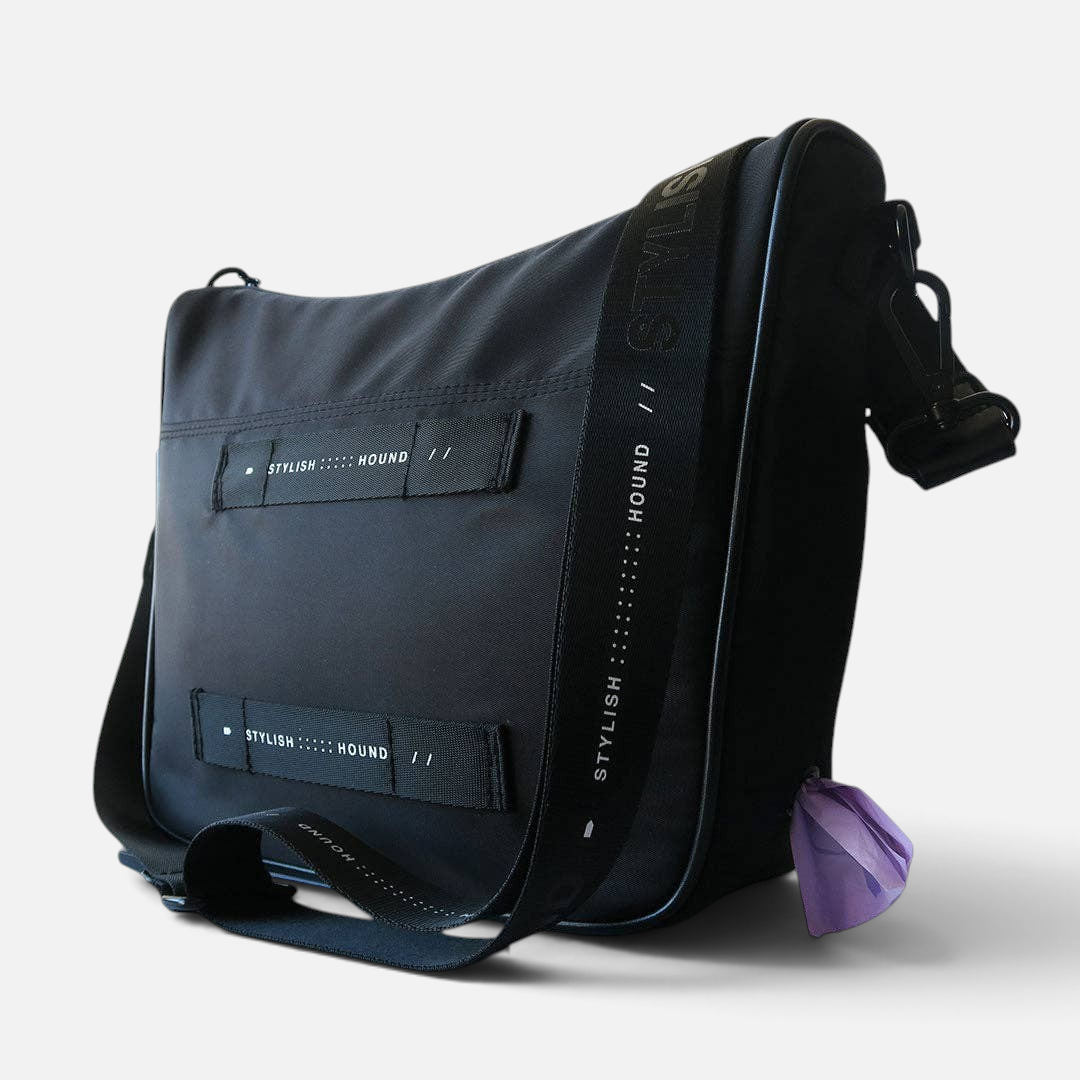 The Dog Emporium Day Tripper bag in black durable canvas with adjustable logo strap and side poop bag dispenser.